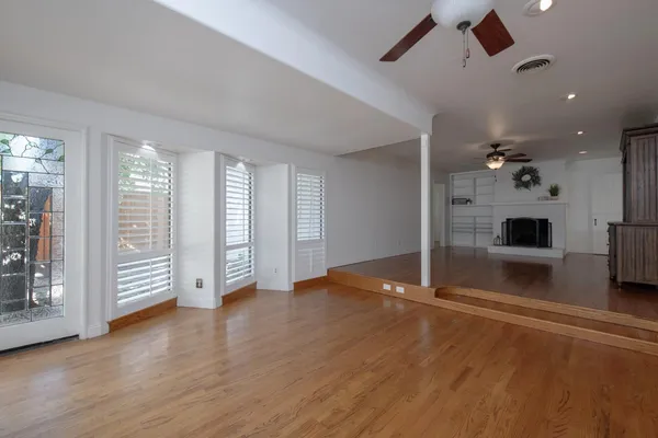 a view of a livingroom with a fireplace a chandelier and wooden floor