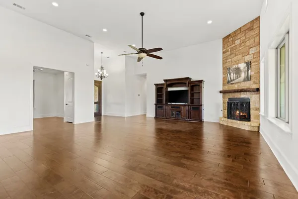 an empty room with wooden floor fireplace and a window