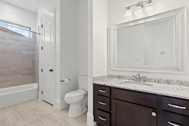 a bathroom with a granite countertop sink toilet a mirror and shower