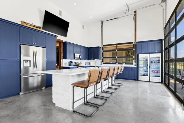 a living room with stainless steel appliances furniture a flat screen tv and kitchen view