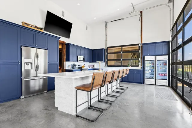 a living room with stainless steel appliances furniture a flat screen tv and kitchen view