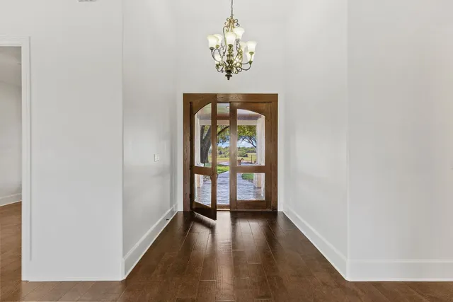 a hallway with wooden floor chandelier and a window