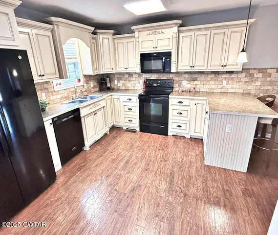 a kitchen with stainless steel appliances a stove top oven a sink a refrigerator a window