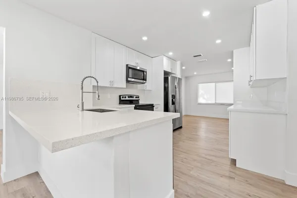 a kitchen with kitchen island a sink appliances and cabinets