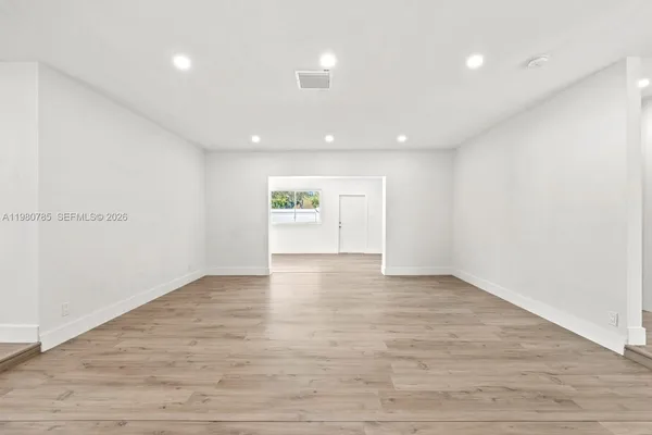 a view of an empty room with wooden floor