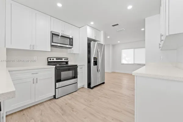 a kitchen with stainless steel appliances white cabinets and wooden floors