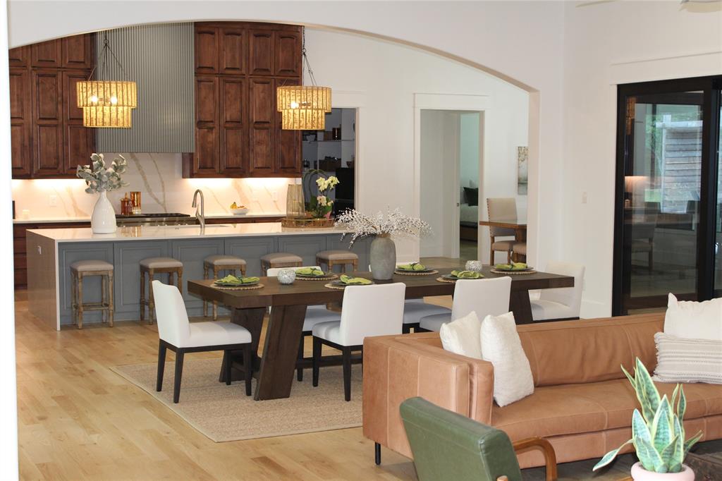 333 Renaissance Lane Heath, TX 75032 - Photo 14 of 35 Open-concept living area featuring light wood-finish flooring, a kitchen with a gray island and white countertop, dark wood cabinetry, and a dining area with a wood table