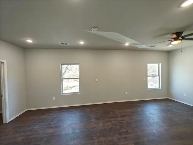 an empty room with wooden floor and windows