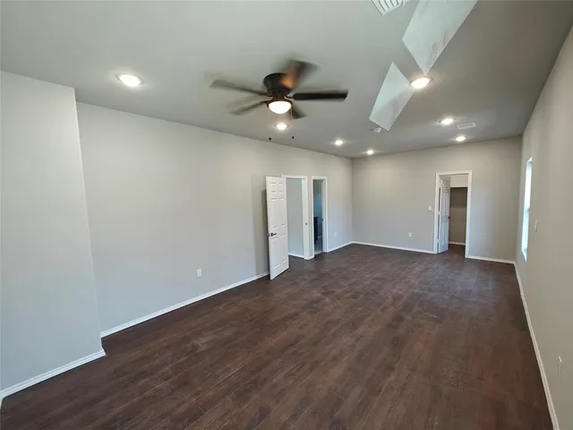 an empty room with wooden floor ceiling fan and windows