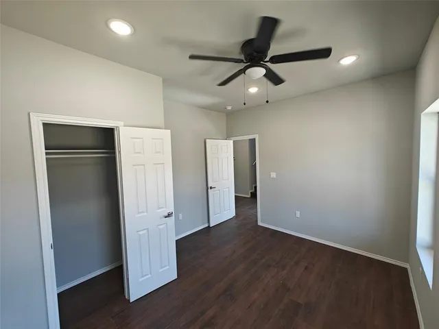 an empty room with wooden floor and ceiling fan