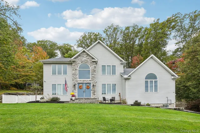 a view of a white house with a big yard and large trees