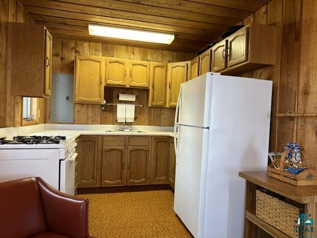 2763 Van Vac Road Ely, MN 55731 - Photo 7 of 37 Kitchen area with wood paneling and cabinetry, featuring a white gas range, a white refrigerator, and a white countertop with an integrated sink
