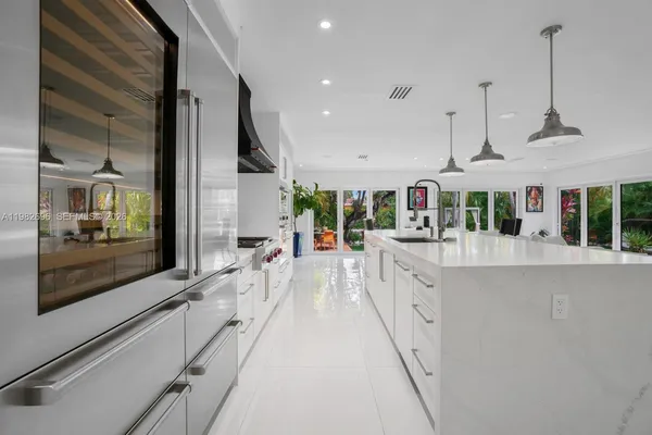 a large white kitchen with kitchen island a large window in it