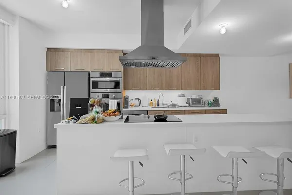 a kitchen with stainless steel appliances a sink a stove a refrigerator cabinets and a window