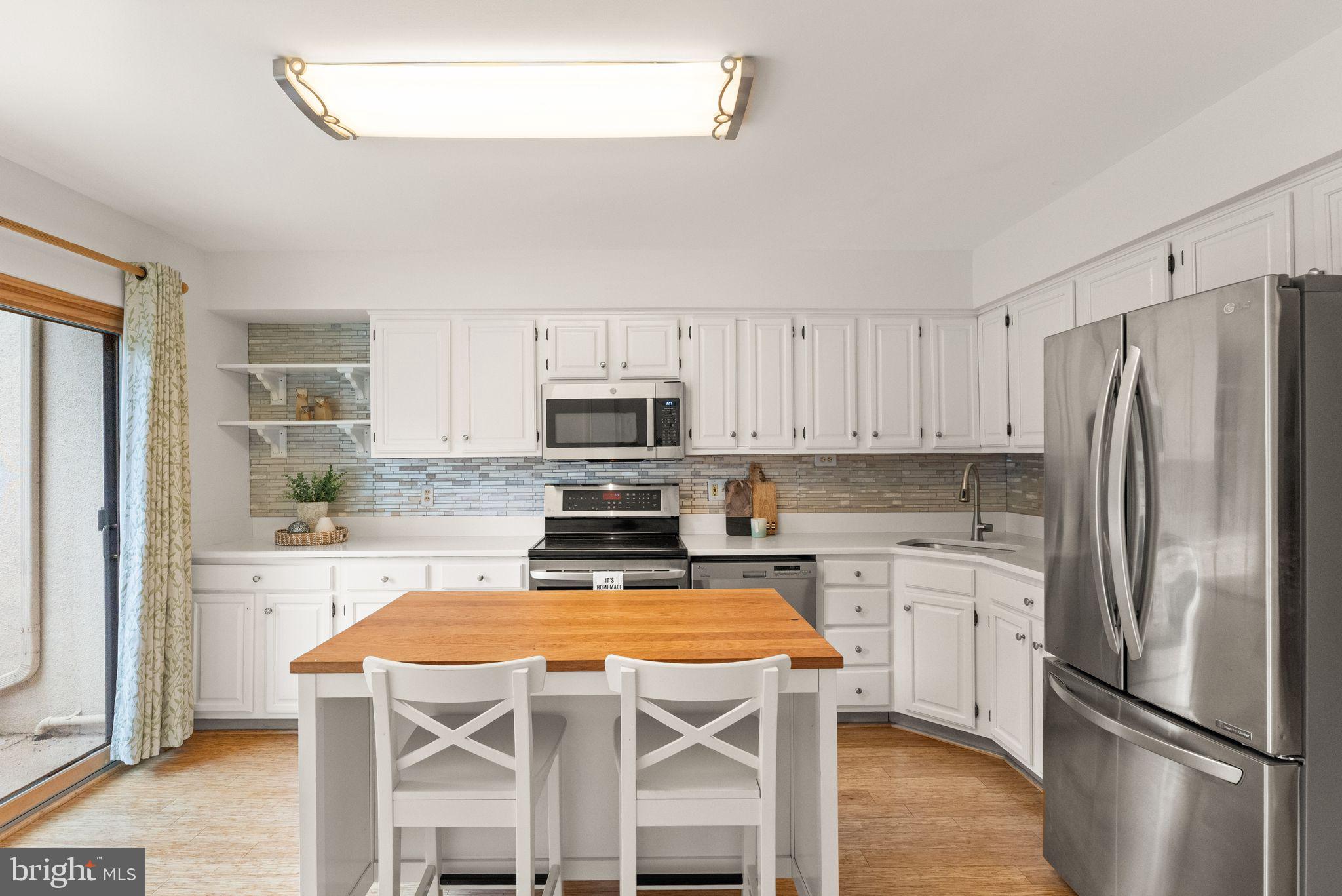 11645 Newbridge Court Reston, VA 20191 - Photo 9 of 62 a kitchen with stainless steel appliances a refrigerator a stove a sink dishwasher and white cabinets with wooden floor