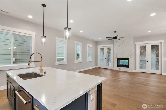 a kitchen with kitchen island a sink stainless steel appliances and wooden floor