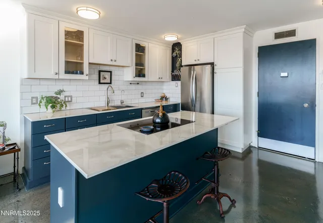 a kitchen with stainless steel appliances a sink a stove a refrigerator and cabinets