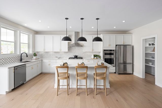 a kitchen with stainless steel appliances kitchen island granite countertop a stove a sink a refrigerator and white cabinets with wooden floor