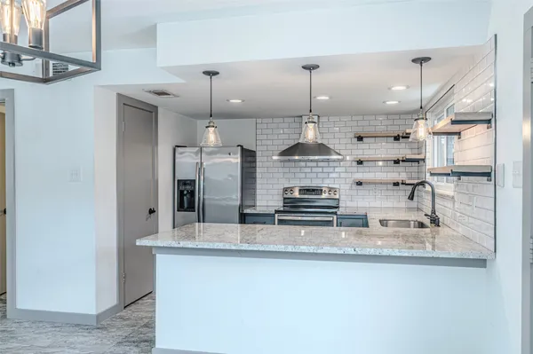 a kitchen with stainless steel appliances granite countertop a sink a stove and a refrigerator