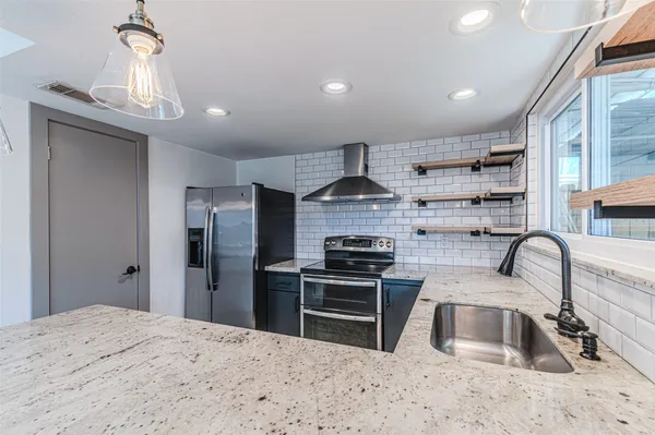 an empty room with wooden floor chandelier fan and windows