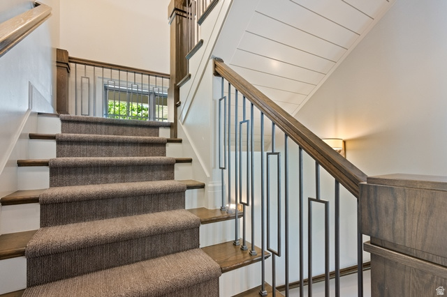 3 Carriagewood Cove, Unit 1088 Sandy, UT 84092 - Photo 31 of 79 Staircase featuring wood-finish treads, a carpet runner, and a custom wrought iron railing with wood-finish handrail and newel posts
