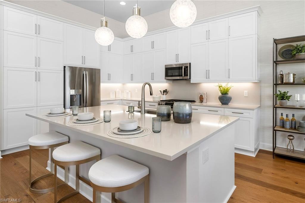 2695 Ridgecrest Place Naples, FL 34112 - Photo 10 of 13 Kitchen featuring appliances with stainless steel finishes, light wood-style floors, white cabinets, a kitchen breakfast bar, and recessed lighting