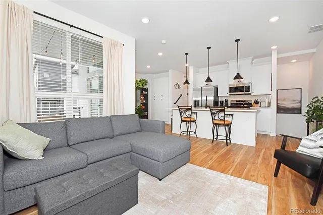 a kitchen with stainless steel appliances kitchen island granite countertop a stove a sink a center island a refrigerator and a wooden floor