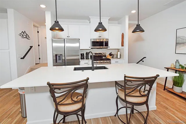 a kitchen with stainless steel appliances kitchen island granite countertop a table chairs and a wooden floor