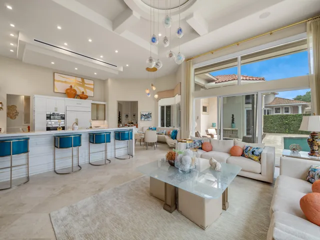 a living room with furniture kitchen view and a large window
