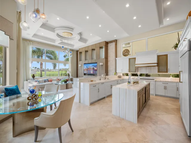 a large kitchen with cabinets chairs and chandelier