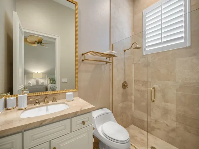 a bathroom with a granite countertop sink toilet a mirror and shower