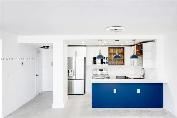 a kitchen with stainless steel appliances kitchen island granite countertop a refrigerator and a sink