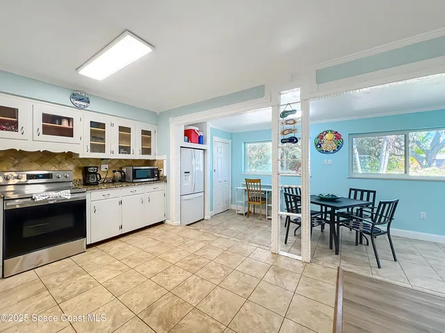 a view of kitchen with stainless steel appliances granite countertop a stove top oven a dining table and chairs with wooden floor