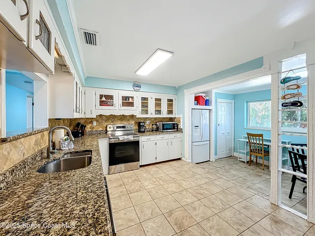 a kitchen with a stove a refrigerator and white cabinets