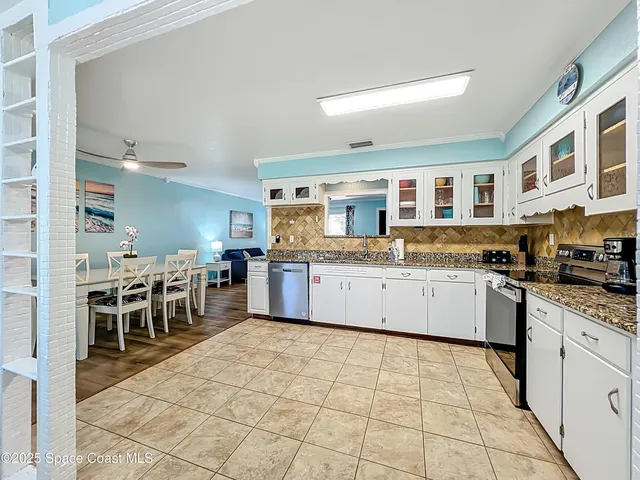 a kitchen with stainless steel appliances granite countertop a stove top oven a sink a dining table and chairs