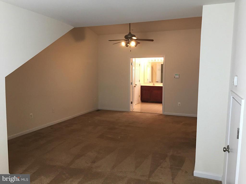 74 Backstretch Way Prince Frederick, MD 20678 - Photo 13 of 21 an empty room with a chandelier fan and windows