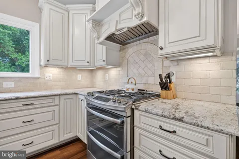 a kitchen with granite countertop stainless steel appliances white cabinets and a stove