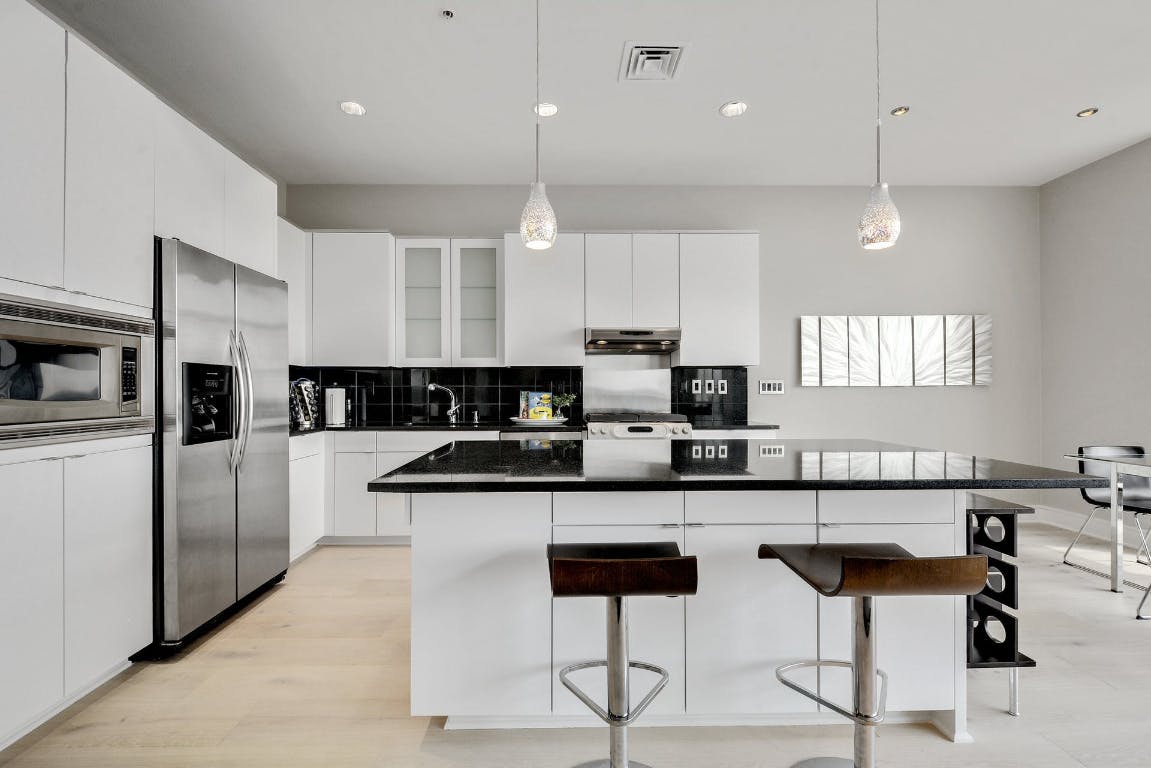 555 East 5th Street, Unit 723 Austin, TX 78701 - Photo 7 of 18 a kitchen with stainless steel appliances kitchen island granite countertop a sink and cabinets