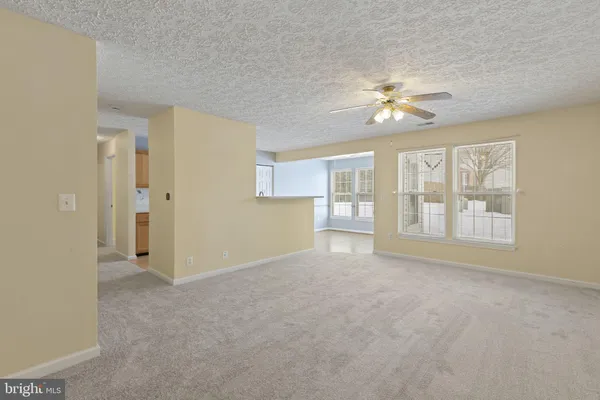an empty room with chandelier fan and windows