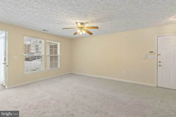 an empty room with windows and chandelier fan