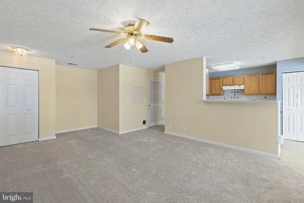 a view of an empty room with chandelier fan and a window