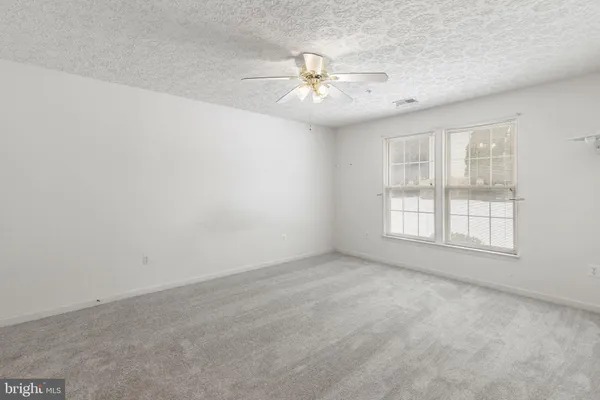 an empty room with windows and chandelier fan