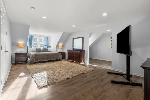 a view of a hallway view with wooden floor and a bathroom