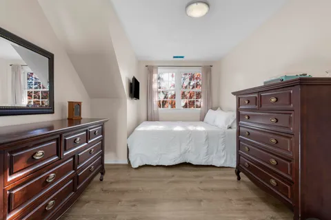 a bedroom with a bed and a flat tv screen on dresser