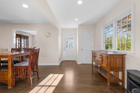 a kitchen with stainless steel appliances granite countertop a stove top oven a refrigerator a sink and a dining table with white cabinets