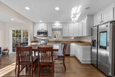 a open dining room with stainless steel appliances granite countertop a kitchen island a stove a table and chairs
