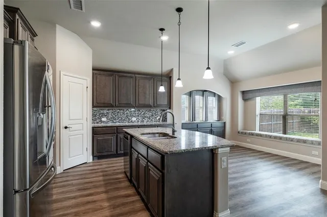 a kitchen with stainless steel appliances granite countertop a sink refrigerator and wooden floor