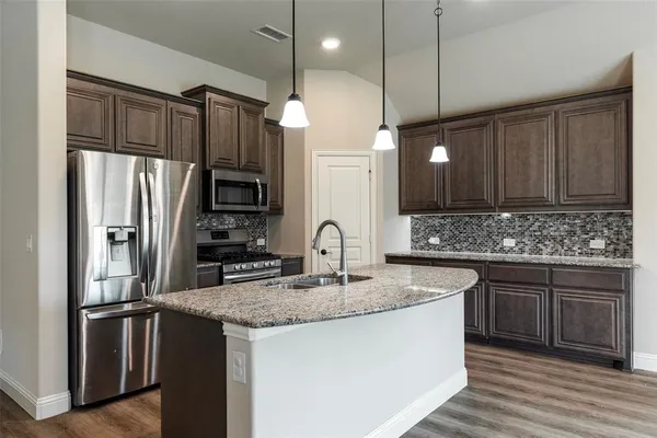 a kitchen with stainless steel appliances granite countertop a sink refrigerator and cabinets