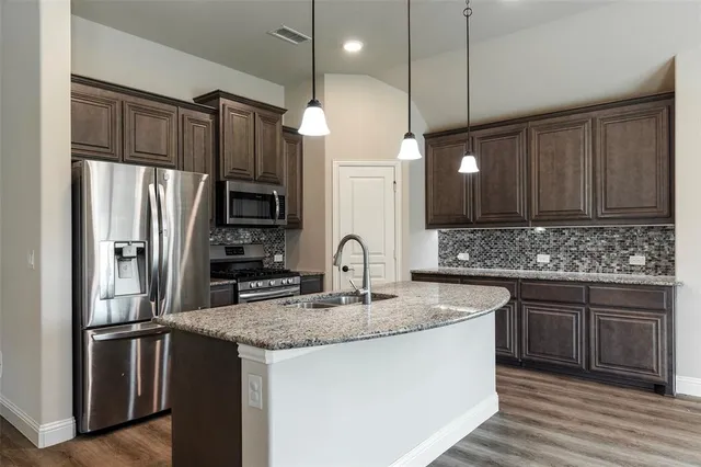 a kitchen with stainless steel appliances granite countertop a sink refrigerator and cabinets