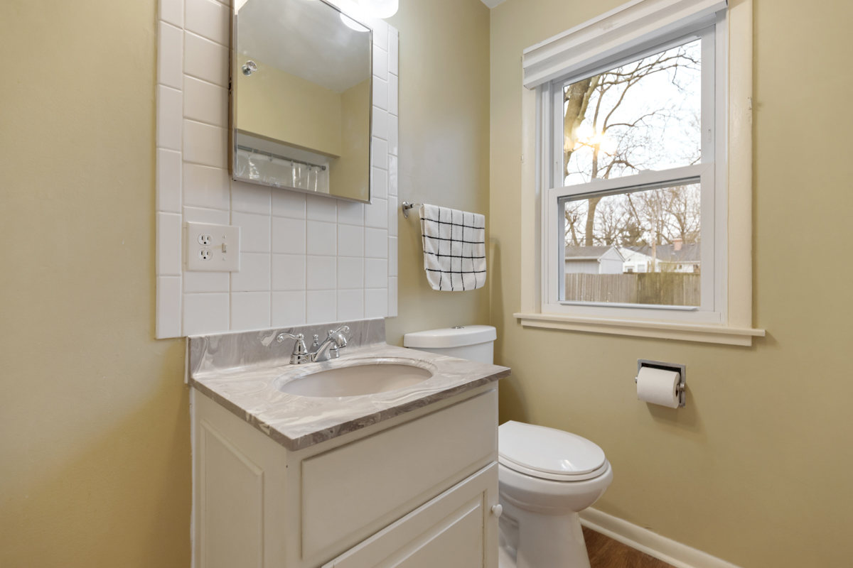 610 High Street Geneva, IL 60134 - Photo 12 of 18 a bathroom with a granite countertop toilet a sink and a window